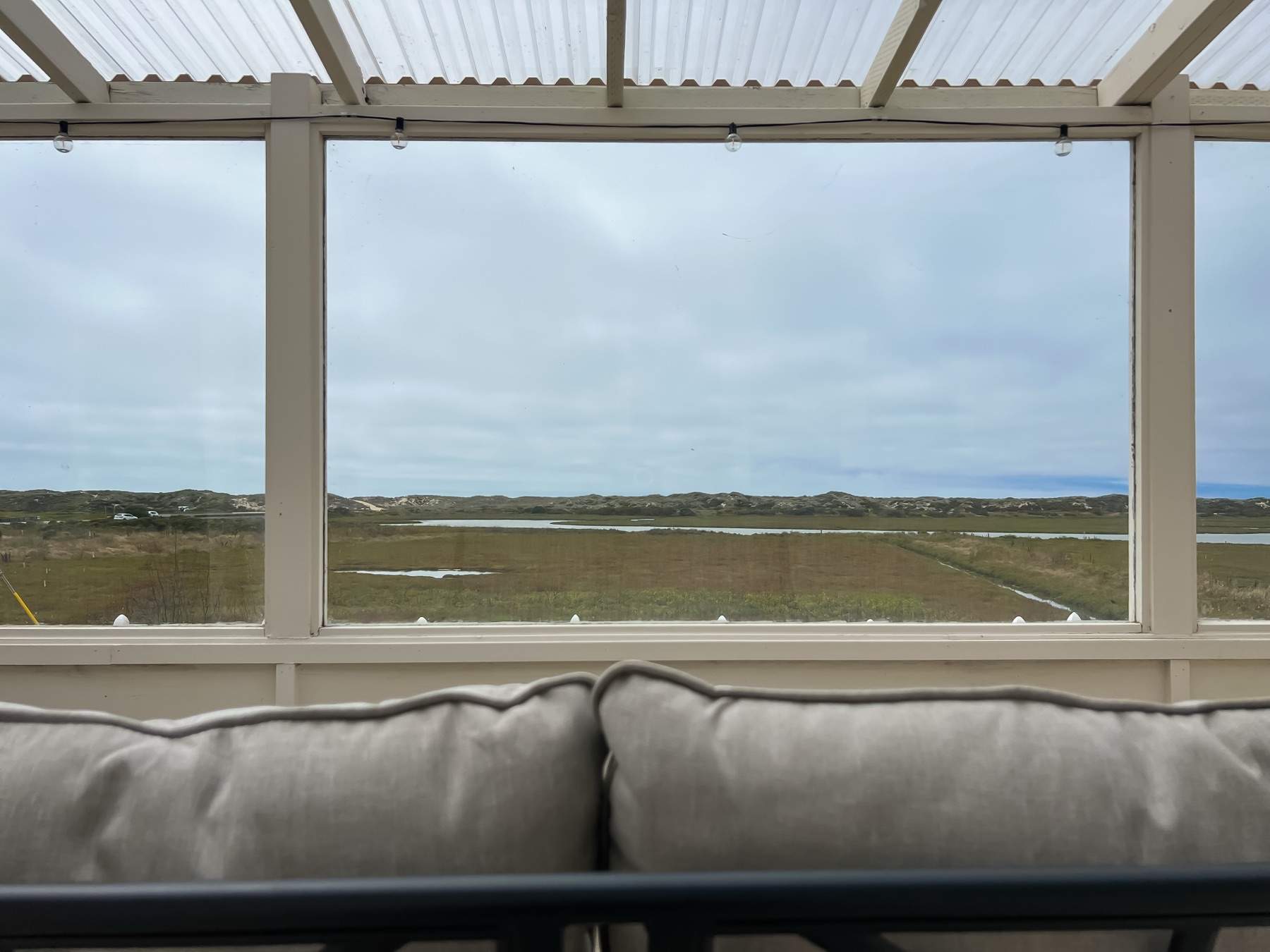 A sunroom with comfortable seating looking out over the Moss Landing wetlands and dunes